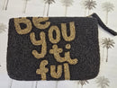 Black beaded clutch with gold text 'Be You Ti Ful' on a patterned background