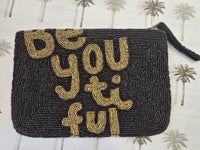 Black beaded clutch with gold text 'Be You Ti Ful' on a patterned background
