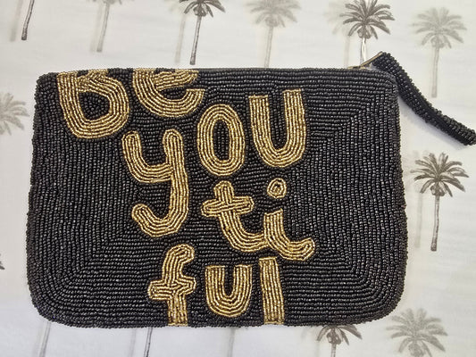 Black beaded clutch with gold text 'Be You Ti Ful' on a patterned background
